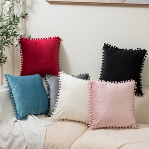 Velvet decorative throw pillow covers with pom-pom edges in multiple colors on a sofa