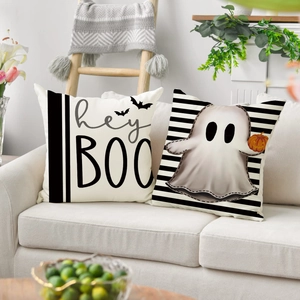 Close-up of Halloween linen pillow covers with ghosts and bats on a cozy white sofa
