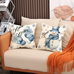 Christmas pillow covers with snowman and mittens prints on a cozy sofa setting