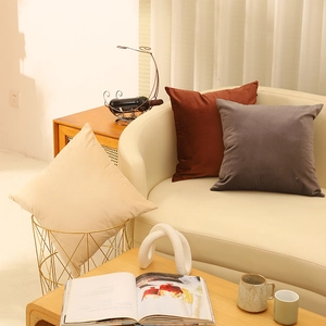Modern velvet cushion covers in beige, red and grey displayed on a sofa in a cozy living room