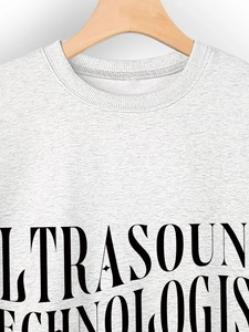 Detail eines grauen Sweatshirts mit Ultrasound Technologist Aufdruck auf Holzbügel
