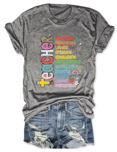 Dettaglio della t-shirt grigia da insegnante con scritte colorate e pantaloncini denim