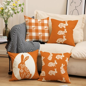 Set of four Easter linen pillow covers with orange rabbit prints on a cozy sofa
