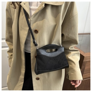Detail of black quilted shoulder bag featuring contrast textures and silver hardware