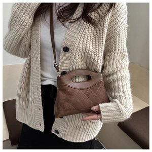 Detail of dark brown quilted crossbody bag with top handle and adjustable shoulder strap
