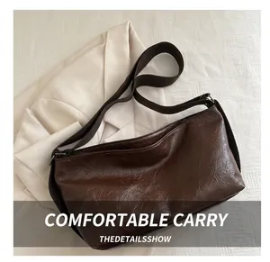 Détail du sac cabas en cuir brillant marron foncé avec large bandoulière tissée chic