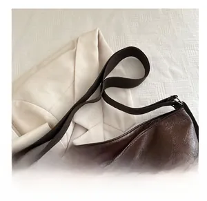 Dettaglio della borsa tote in pelle lucida marrone scuro con ampia tracolla in tessuto