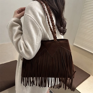 Bohemian dark brown fringe shoulder bag with braided strap worn over a white coat
