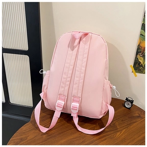 Rear view of pink school backpack with adjustable straps and side pockets on wooden table