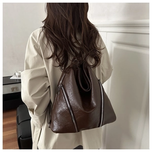 Détails du sac à dos vintage en cuir marron avec zips argentés porté par un modèle