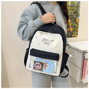 Detail of black and white cartoon backpack featuring transparent PVC pocket and badges