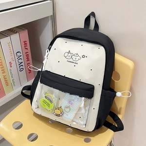 Detail view of school backpack showing transparent PVC front pocket with cartoon pins
