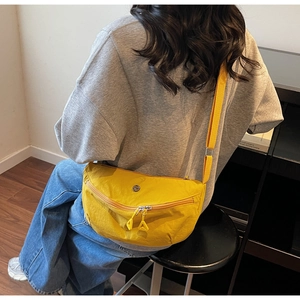 Detail of a bright yellow nylon crescent crossbody bag with adjustable strap and logo