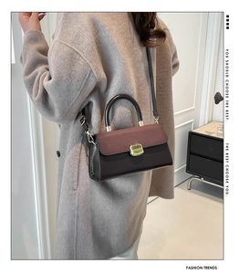 Detail of vintage bicolor crossbody bag with metal lock worn on grey wool coat