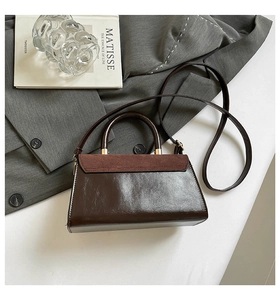 Detail of dark brown leather handbag with suede flap and light gold metal hardware