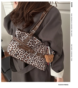 Leopard print tote bag with adjustable brown leather strap and plush bear charm detail