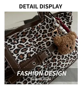 Macro detail of leopard print tote bag with brown leather trim and fluffy bear charm
