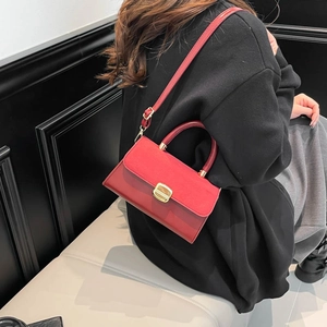 Fashion burgundy leather crossbody bag with gold buckle shown on a model against dark backdrop