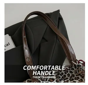 Detail of leopard print tote bag with adjustable brown leather handle and silver metal buckle