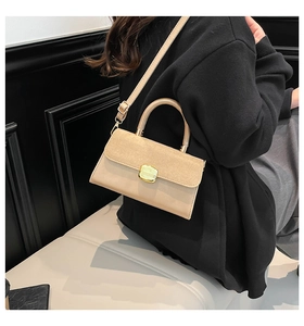 Detail of a chic two-tone handbag with suede flap and gold metal clasp closure