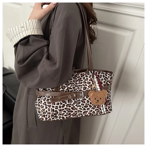 Detail of leopard print tote bag with brown PU leather handle and plush bear pendant