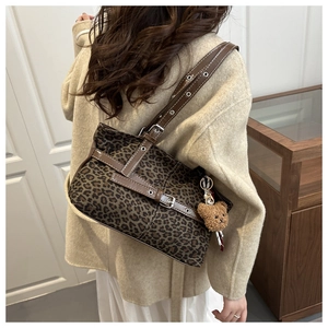 Close-up of leopard print tote bag featuring brown leather trim and a cute plush bear charm