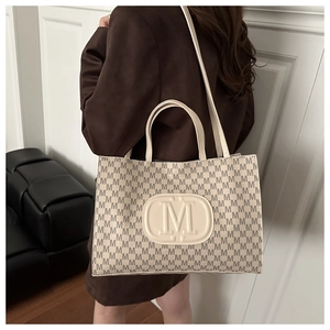 Detail of trendy white tote bag with M print showing spacious design for daily commute