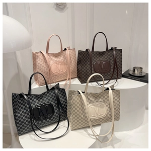 Detail view of monogram tote bags in pink, brown, and black on a minimalist studio display