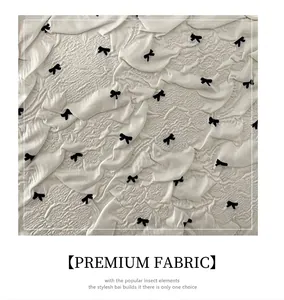 Vue détaillée du tissu gaufré blanc orné de petits motifs de nœuds papillon noirs