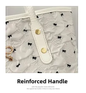Détail du sac cabas gaufré blanc avec nœuds noirs et rivets dorés de renfort de poignée