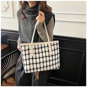 Detail view of large canvas tote bag with black and white woven texture and metal rivets