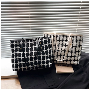 Detail of classic tweed plaid tote bags with metallic rivets and long shoulder straps