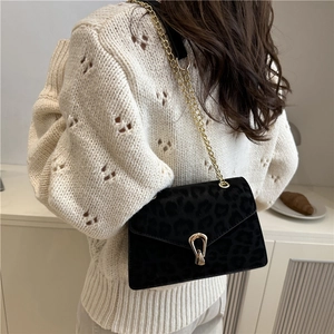Chic black leopard print chain crossbody bag with gold buckle on a knitted sweater