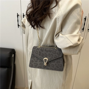 Retro grey leopard print crossbody bag with gold chain strap shown on a beige coat