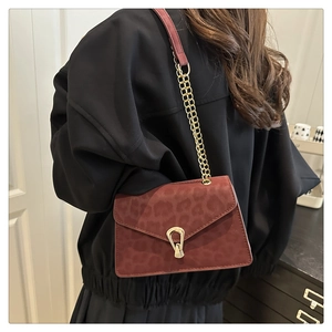 Detail of burgundy leopard print crossbody bag with gold chain and teardrop buckle
