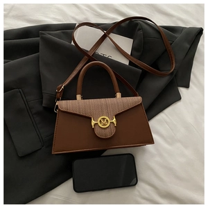 Detail of a brown leather shoulder bag with woven panels and a gold M-shaped metal clasp