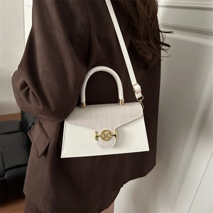 White elegant handbag with woven flap and gold M buckle shown on shoulder of a model