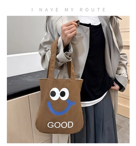 Detail of a brown canvas tote bag with large eye motifs and GOOD printed text