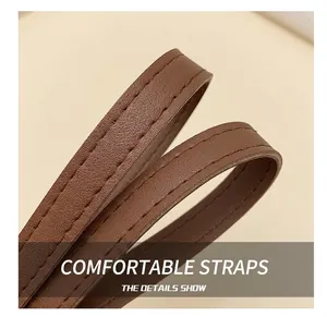Detailed close-up of brown leather shoulder strap with reinforced double stitching