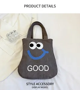 Detail of grey canvas tote bag featuring a cute cartoon face and white GOOD text print