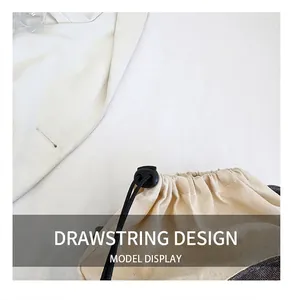Detail view of the drawstring design and black toggle on a beige canvas shoulder bag