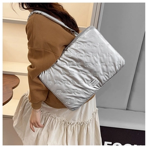 Close-up of silver quilted laptop bag featuring bow patterns and a soft shoulder strap