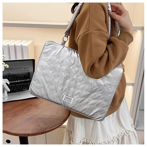 Silver laptop tote bag featuring bow quilting and fashion label, shown with a laptop