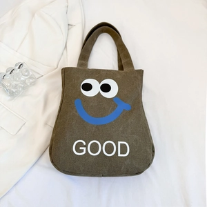 Detail of brown canvas tote bag featuring white GOOD text and cute cartoon smile design