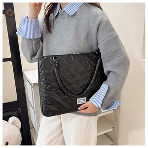 Detail of black quilted laptop bag featuring 3D bow texture and fashion label