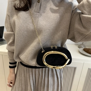 Elegant black evening crossbody bag with gold metal handle and chain strap on model