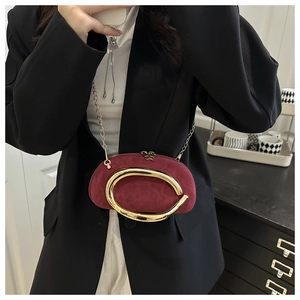 Detail of burgundy suede-textured round bag with large gold metal handle and chain