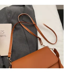 Detail of adjustable leather strap and gold-tone hardware on caramel crossbody bag