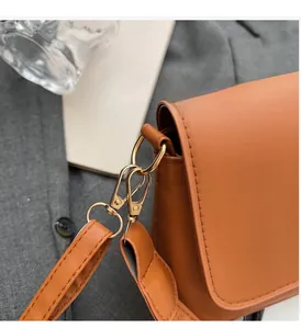 Close-up of golden metallic lock and hardware on a caramel leather crossbody bag