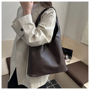 Vista laterale di una grande borsa tote in pelle marrone scuro indossata da una modella